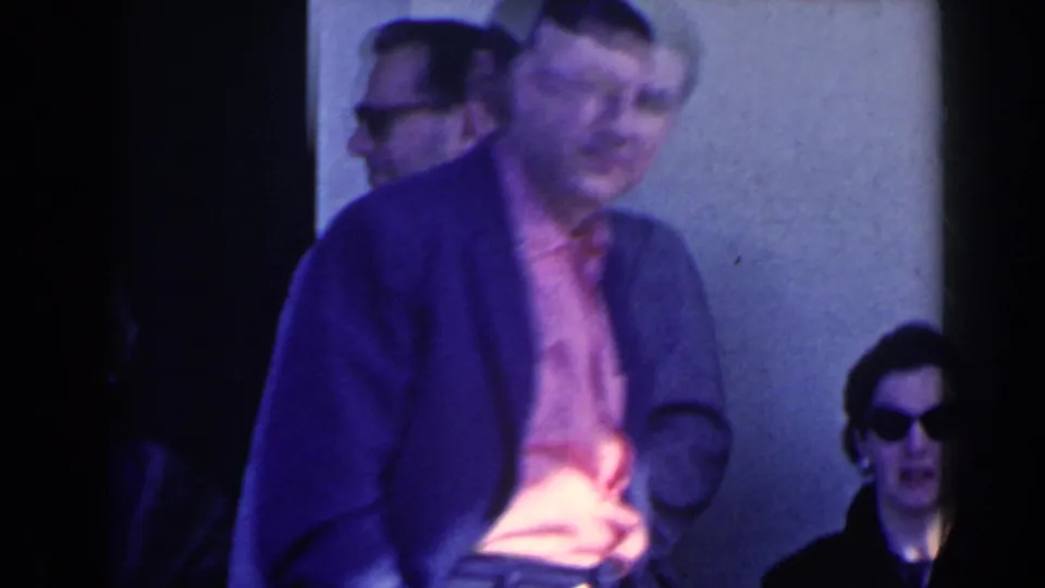 1963 home-movie frame from Niagara Falls, Canada showing people outside a building as a man passes close to the camera.