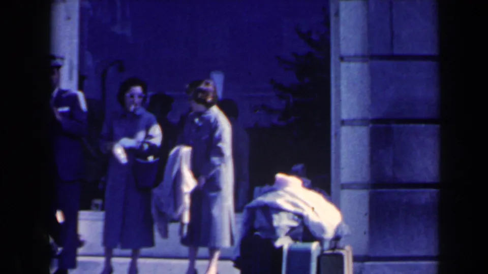 Adults remain near the entrance with luggage, partially obscured by deep shadow and blue 8mm color cast.
