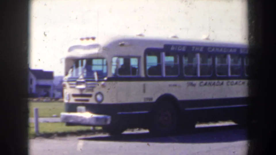 Cream-and-blue Canada Coach Lines bus parked in bright daylight, filmed in a 1963 Niagara Falls, Canada home-movie sequence.