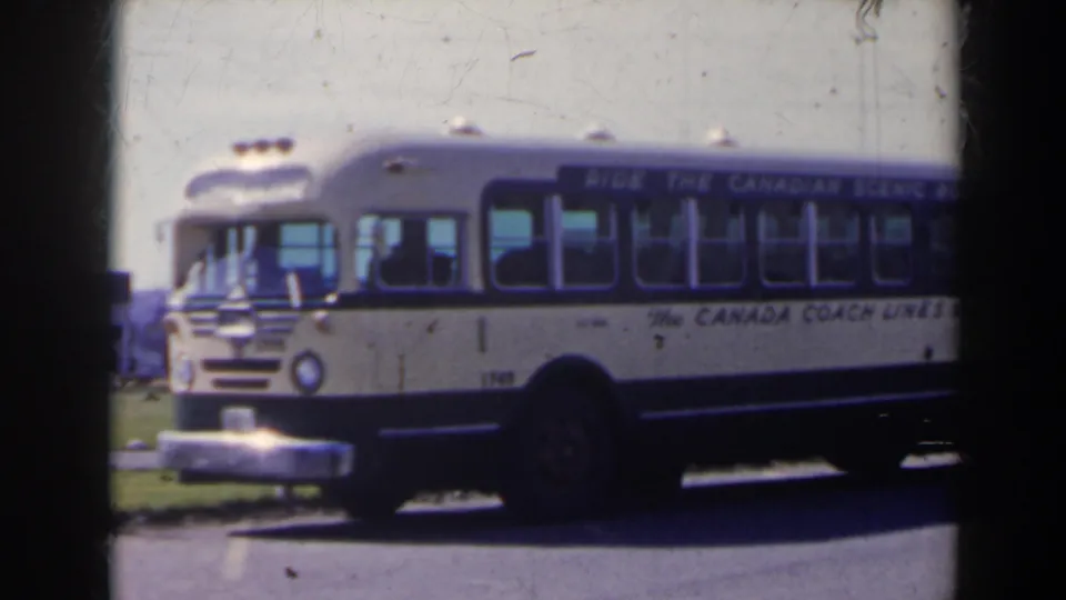 A Canada Coach Lines bus fills the frame in a soft 8mm view, with side lettering and windows visible in the 1963 Canada travel sequence.
