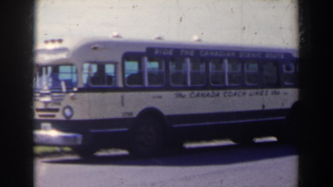 1963 home-movie frame of a blue-and-white Canada Coach Lines bus parked on a roadside in the Niagara Falls, Canada area.
