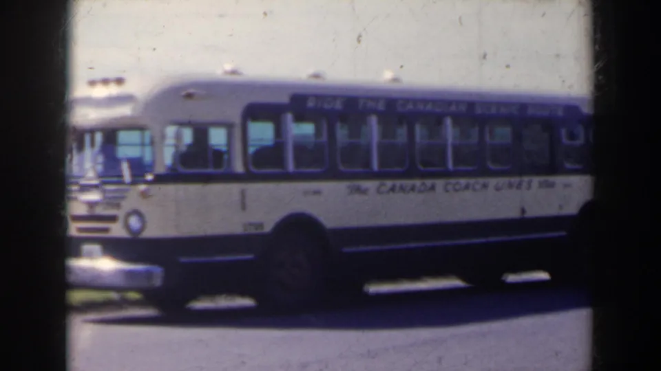 1963 home-movie frame of a blue-and-white Canada Coach Lines bus parked on a roadside in the Niagara Falls, Canada area.