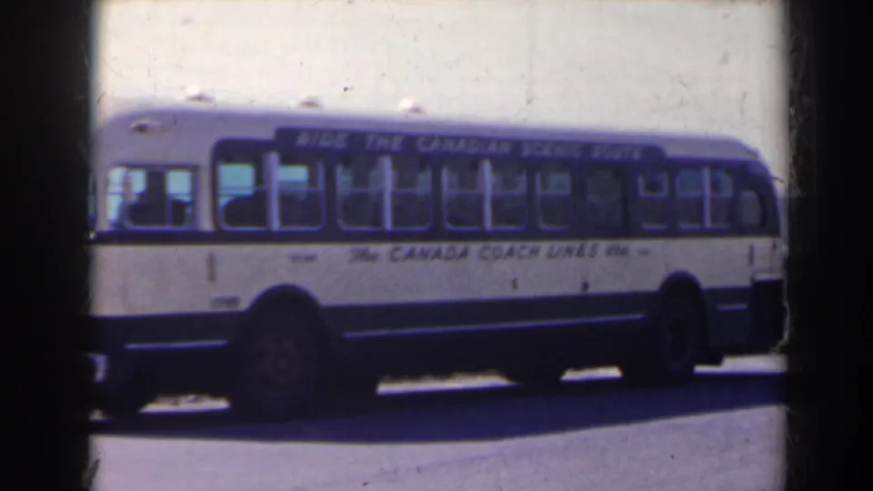 The parked coach fills the frame, with blue window banding, white lower body, and Canada Coach Lines text visible.