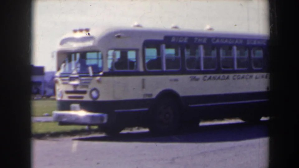 A closer 1963 view shows the front and side of the white and blue Canada Coach Lines bus beside a grassy roadside area.