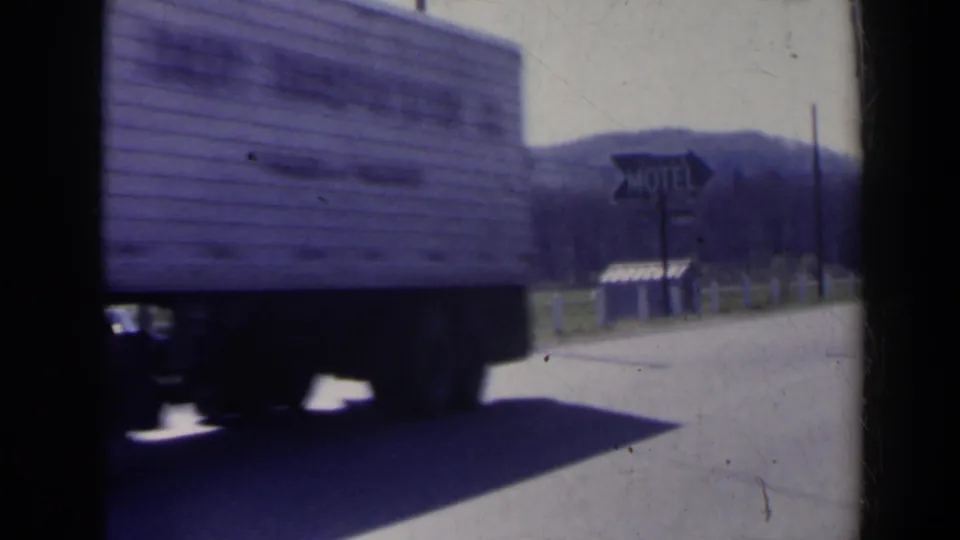 1963 8mm roadside frame near Niagara Falls, Canada, with the truck passing close by and a motel sign visible beyond the road.