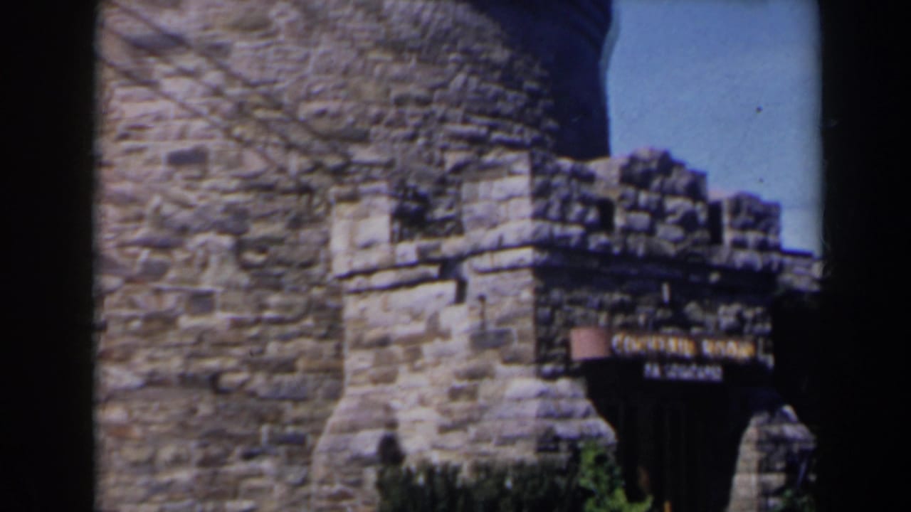 Stone tower and crenellated wall with readable lounge sign at right.