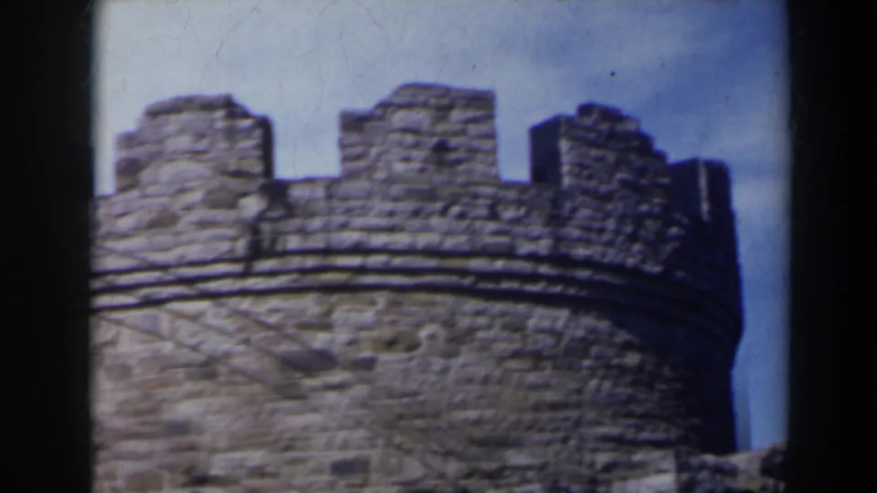 Handheld 8mm view of a castle-like stone tower crown and battlements in the Niagara Falls area, supported by 1963 clip metadata.