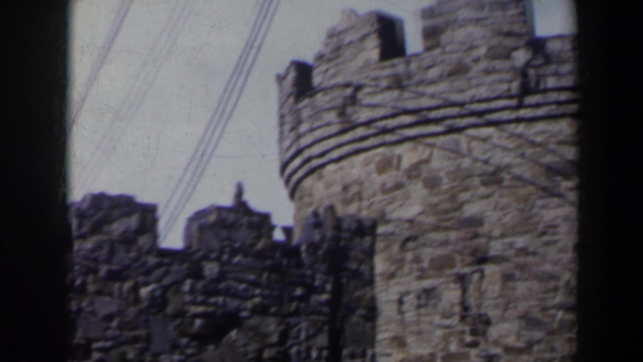 Stone turret and broken-looking wall sections with overhead wires crossing the sky.