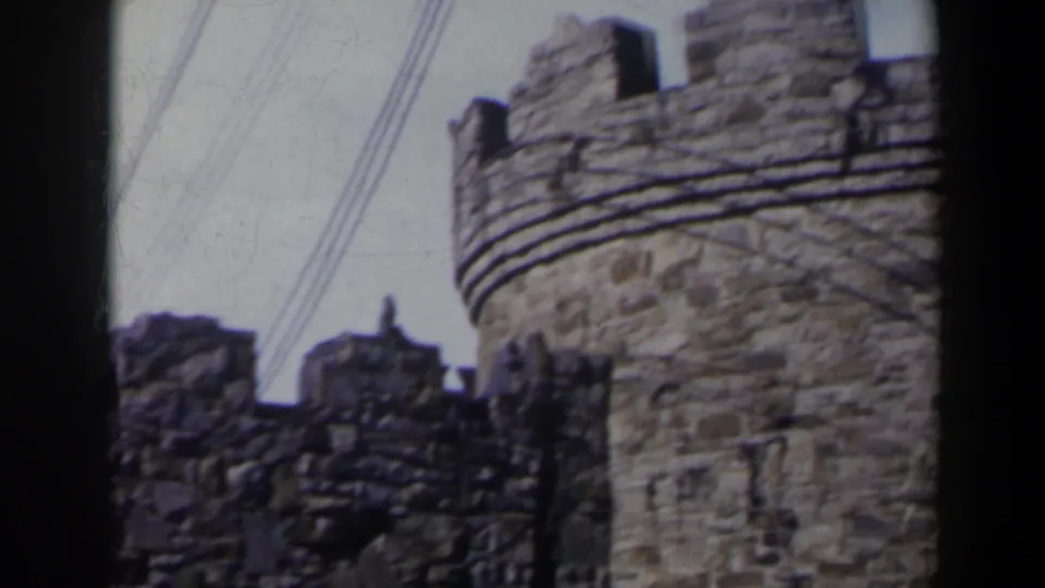 1963 Niagara Falls, Canada frame with a crenelated stone turret, rough wall sections, and overhead power lines above the structure.