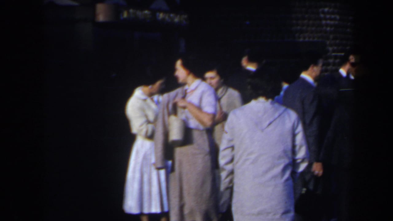 Adults stand in a dim outdoor area near an “AIR CONDITIONED” sign.