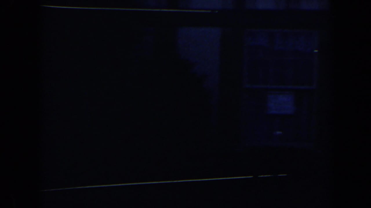 Underexposed 8mm frame from the Niagara Falls clip showing a dark entrance area with little visible activity.