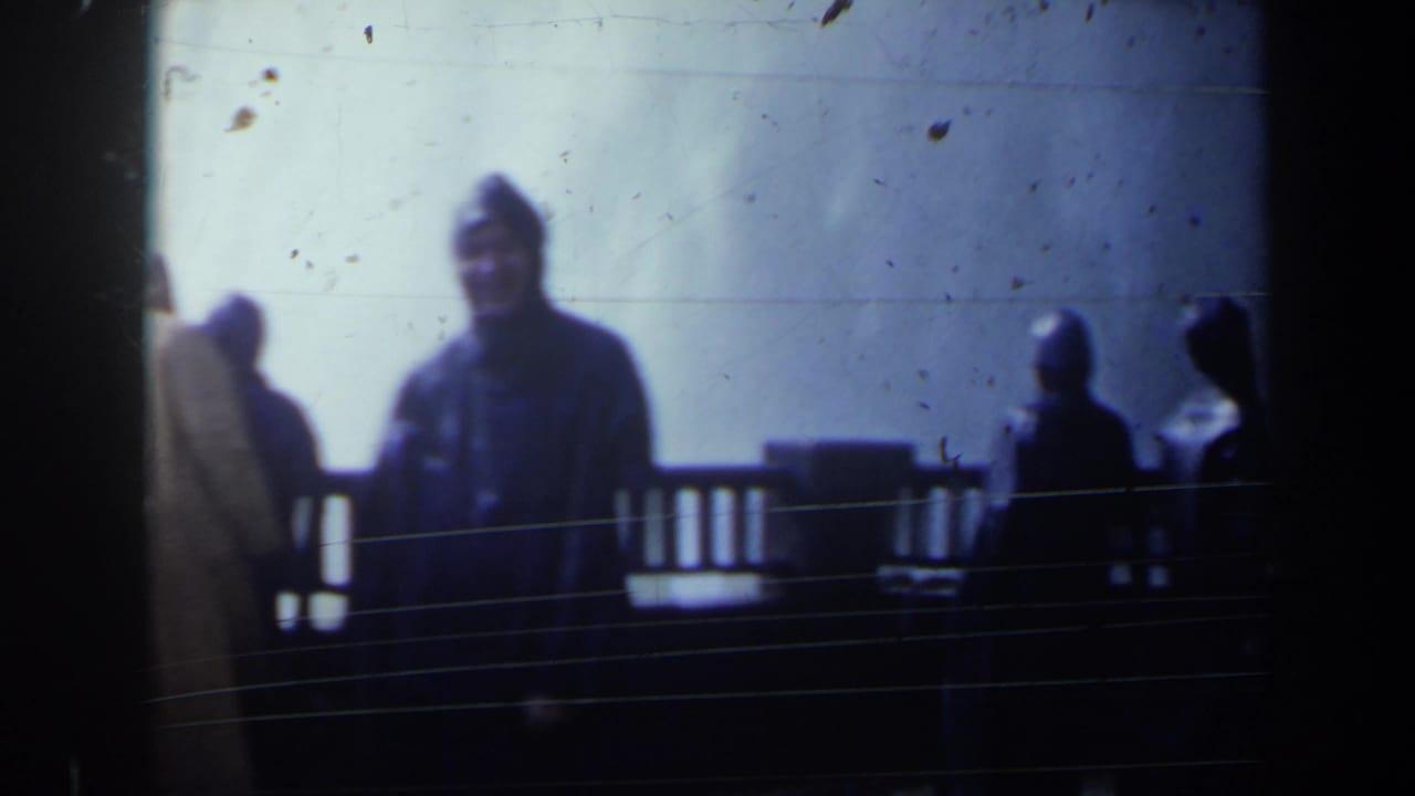 Tourists in raincoats stand near a railing in misty light.
