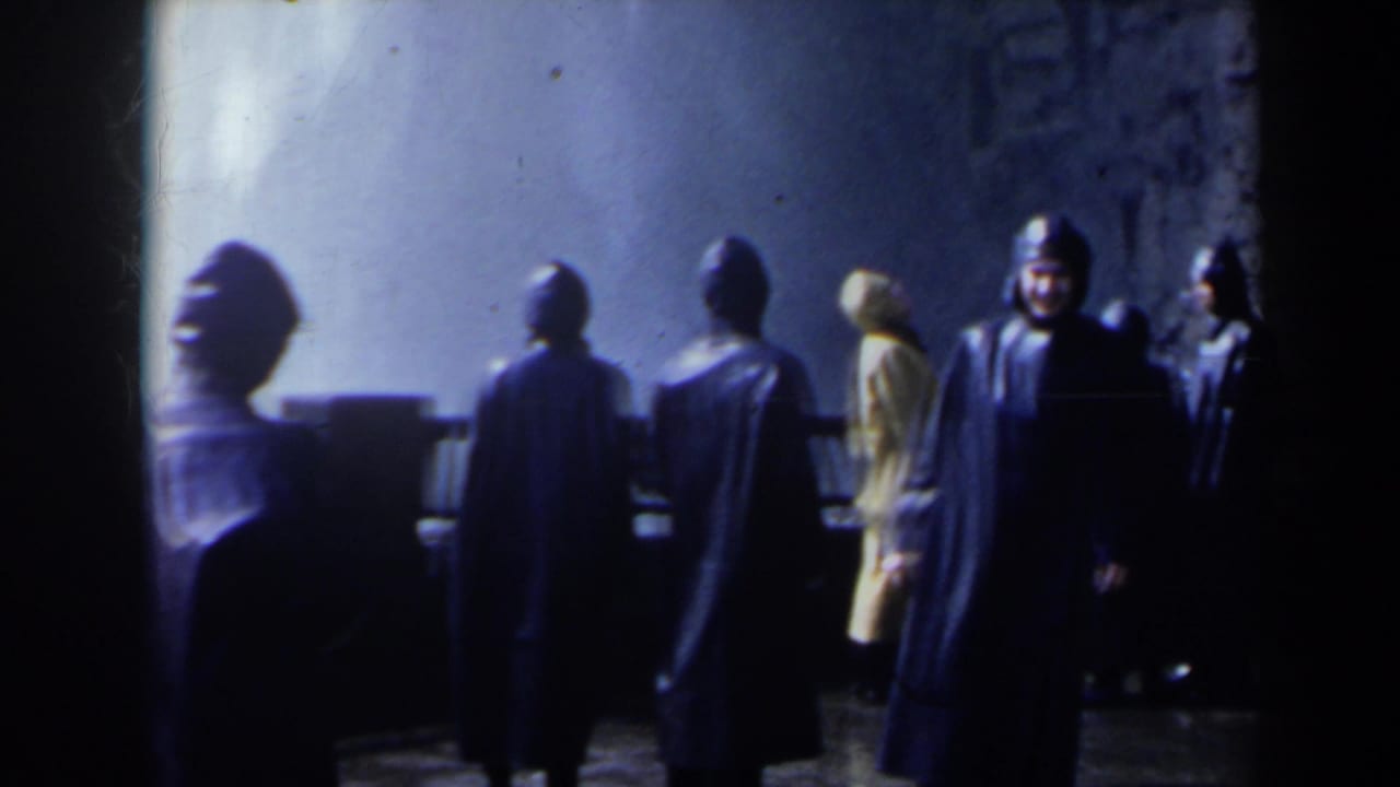 Group of visitors in dark raincoats faces a viewing area wall.