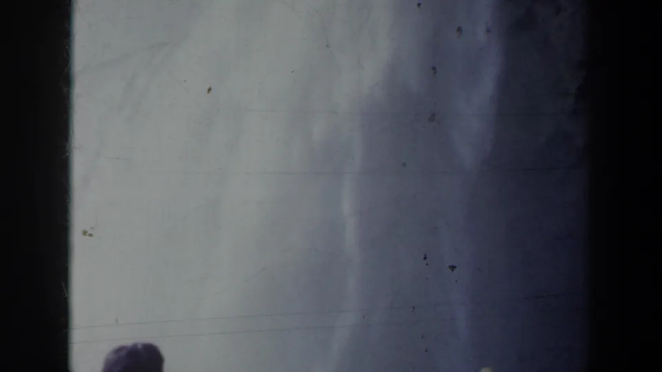 1963 8mm home-movie frame of Niagara Falls mist and spray, with small onlooker silhouettes partly visible at the lower edge.