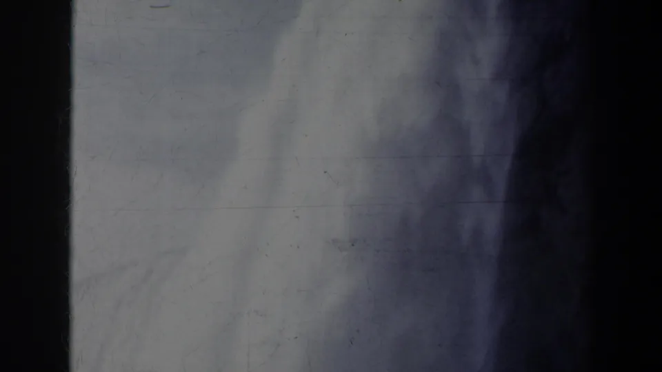 1963 Niagara Falls home-movie frame showing blurred waterfall spray, blue-gray haze, dark gate edges, and worn film texture.