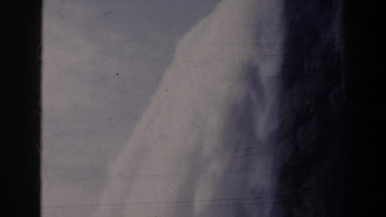 1963 8mm home-movie frame of water dropping beside dark rock, likely at Niagara Falls, Canada, with visible film wear.
