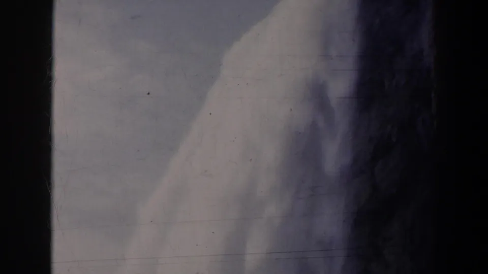 1963 8mm home-movie frame of water dropping beside dark rock, likely at Niagara Falls, Canada, with visible film wear.