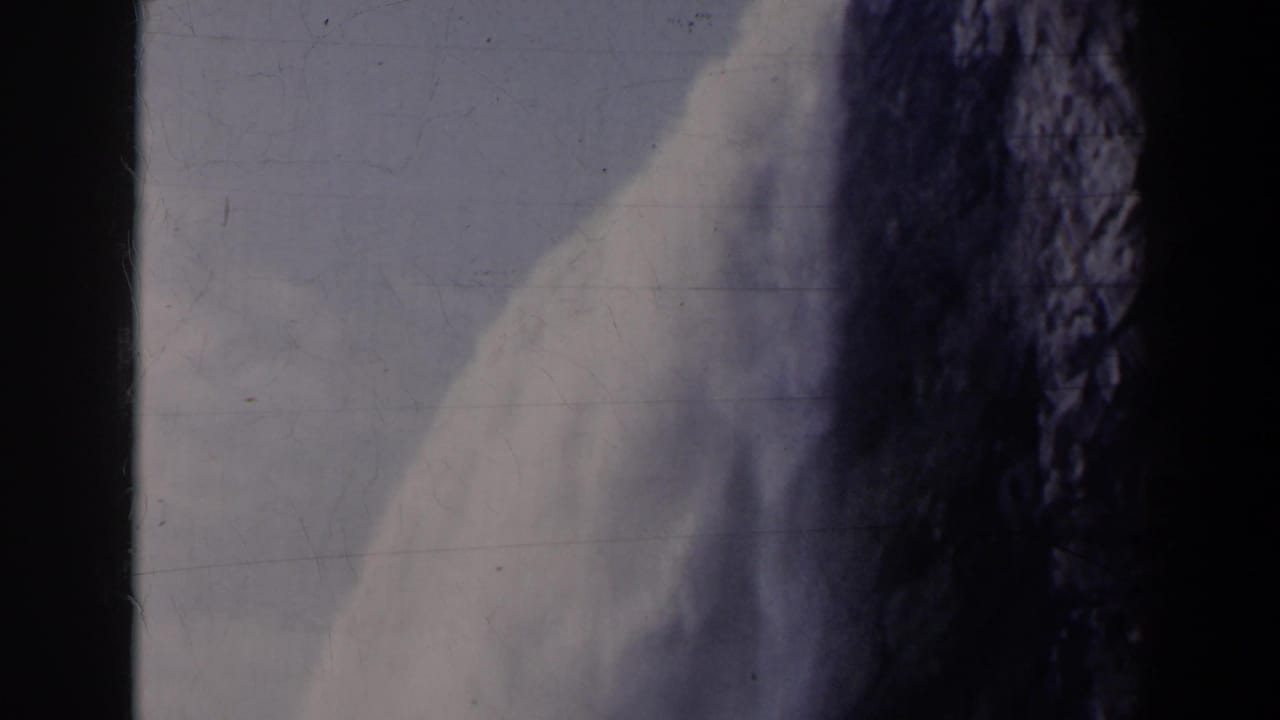Close view of white water and dark cliff with sky in the background.