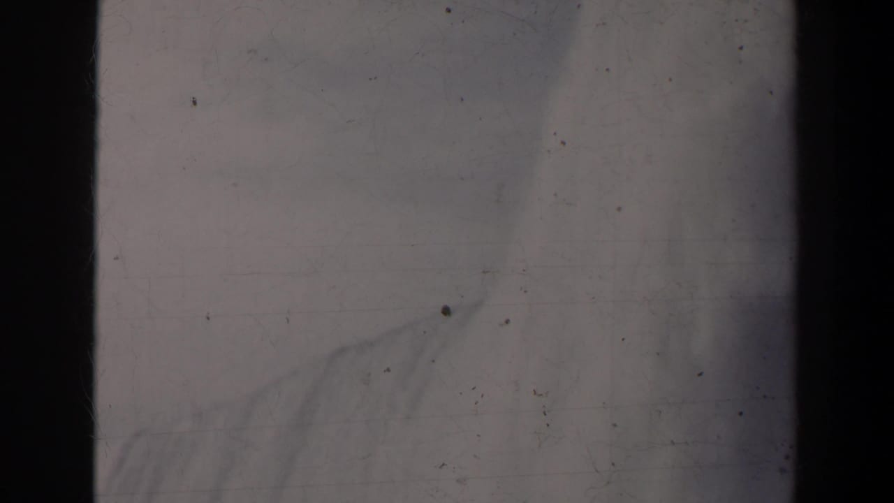 Bright mist and faint waterfall shapes with dark vertical film borders.