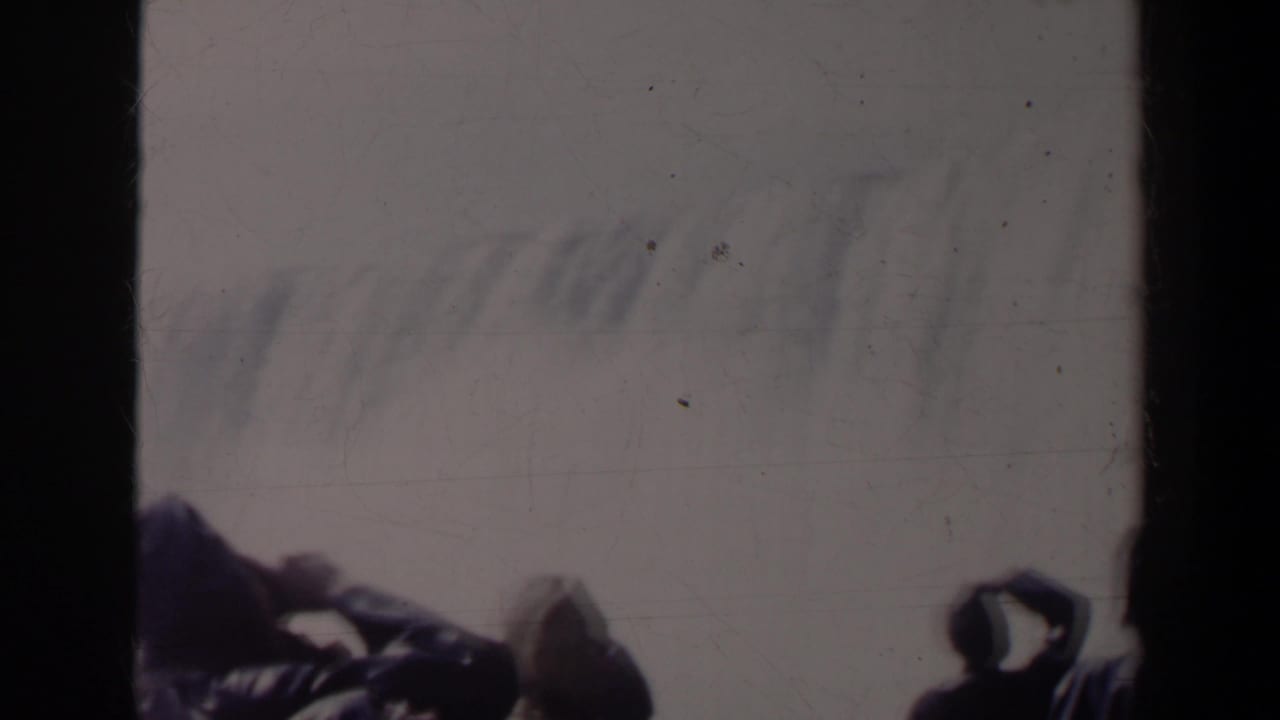 1963 8mm view at Niagara Falls, Canada, with dark silhouetted visitors leaning near a railing against mist and pale sky.