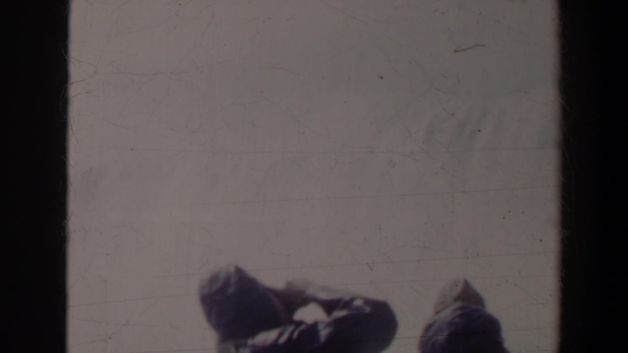 Dark vertical film edge divides a hazy view with people partly visible near the railing.