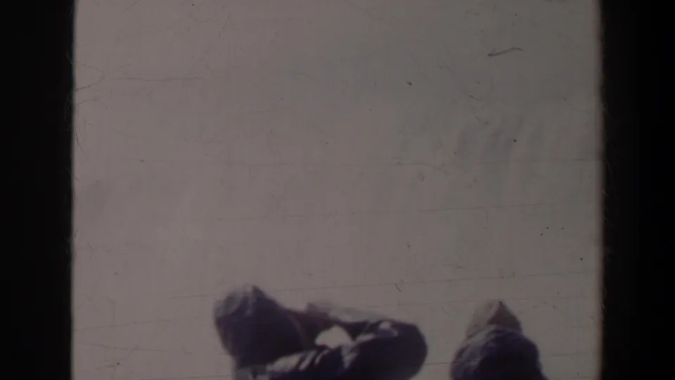A soft 8mm frame shows partial figures at a Niagara Falls overlook, with misty water and a heavy dark border through the center.
