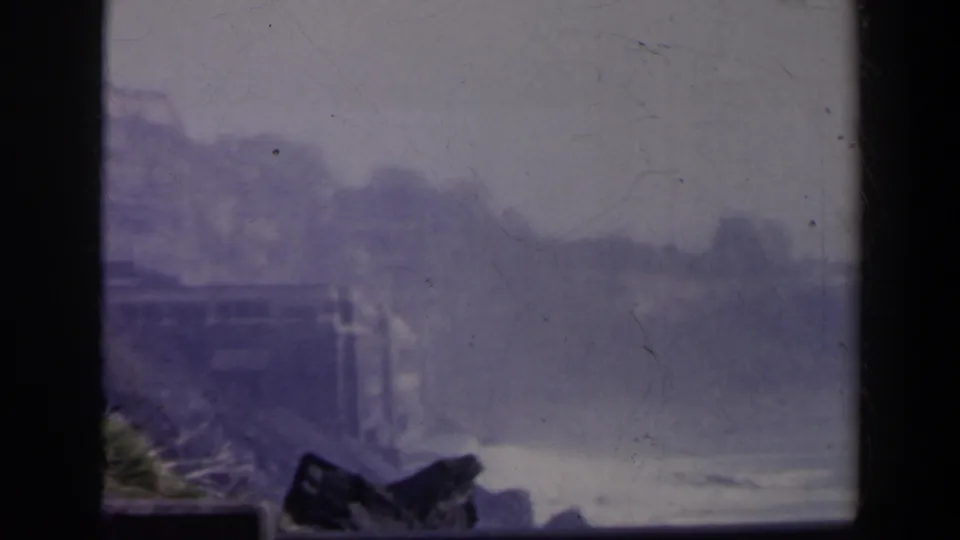 Soft 8mm view across Niagara Falls, Canada, with spray, distant landforms, railing details, and dark foreground shapes.