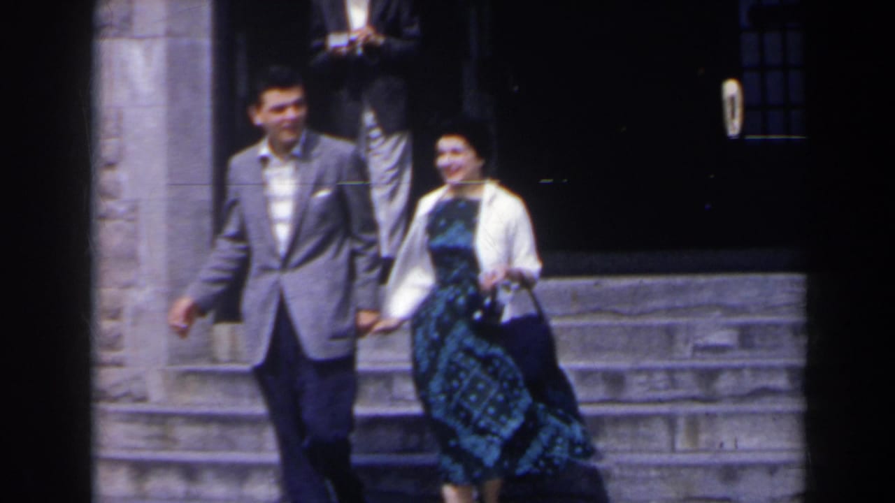 Man and woman walk hand-in-hand down stone steps in bright light.