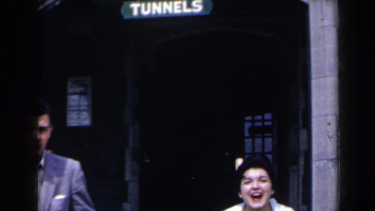 Young man and woman smiling near a stone tunnel entrance marked TUNNELS.
