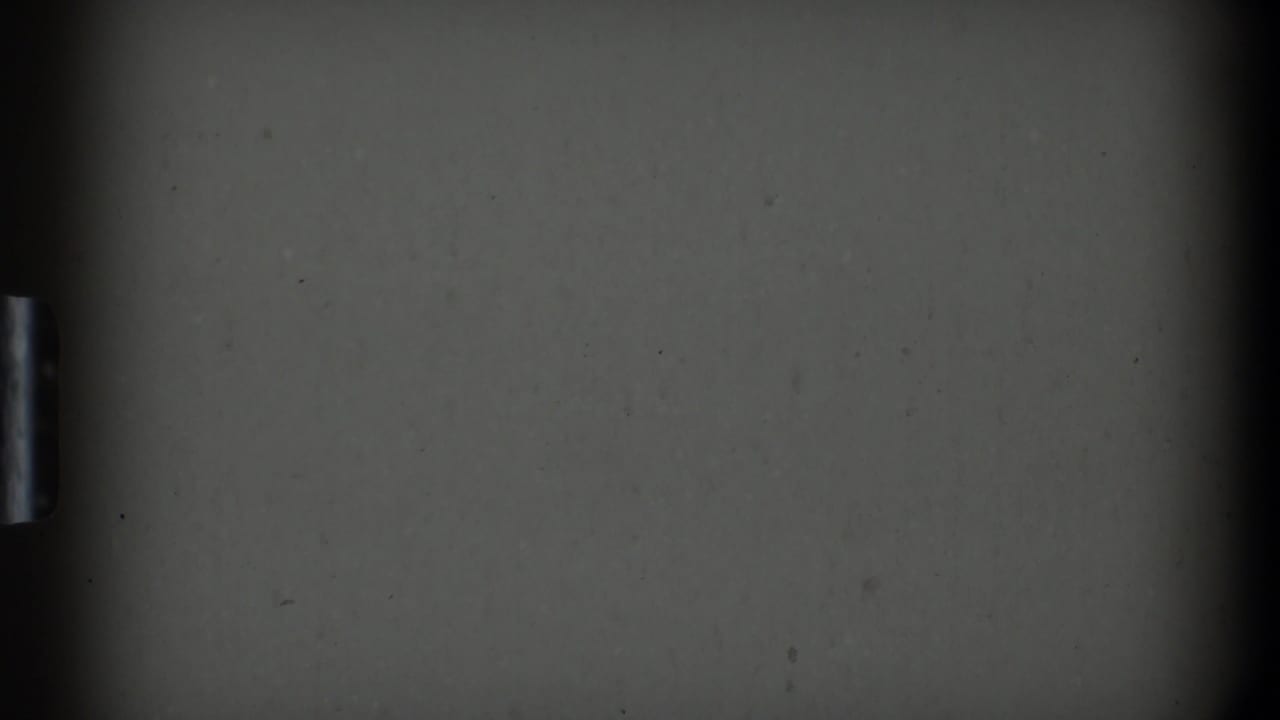 A dim 1969 home-movie frame from Clarendon Hills showing a dark flat cabinet or appliance surface with a small metal handle.