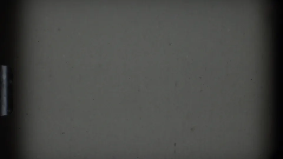 A dim 1969 home-movie frame from Clarendon Hills showing a dark flat cabinet or appliance surface with a small metal handle.