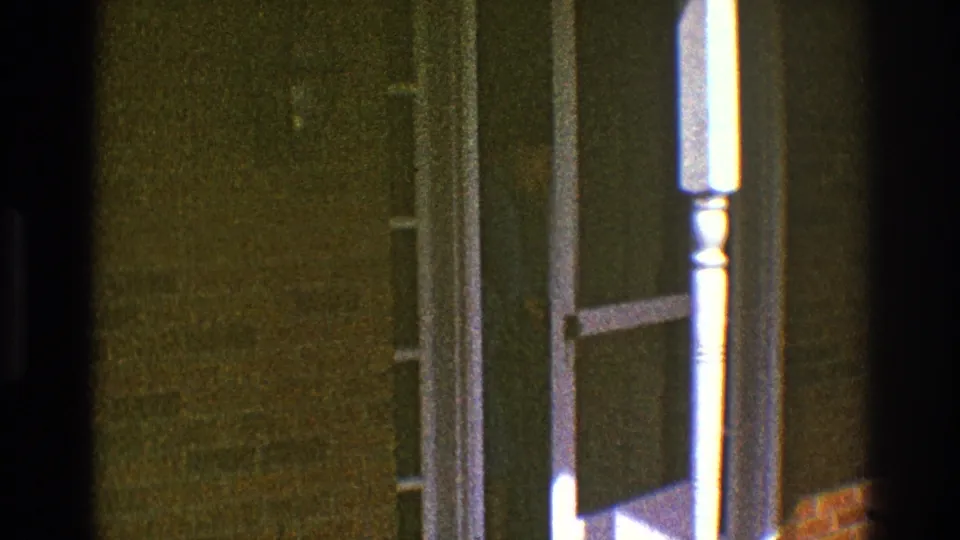 The storm door stands open at the house entrance in the 1969 Clarendon Hills footage, with the white porch post centered in the frame.