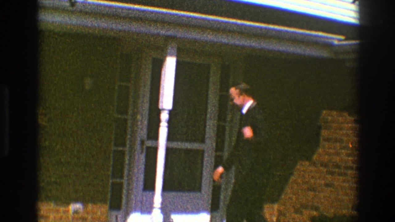 The suited man turns from the camera toward the doorway of a brick home in Clarendon Hills, Illinois, in 1969.