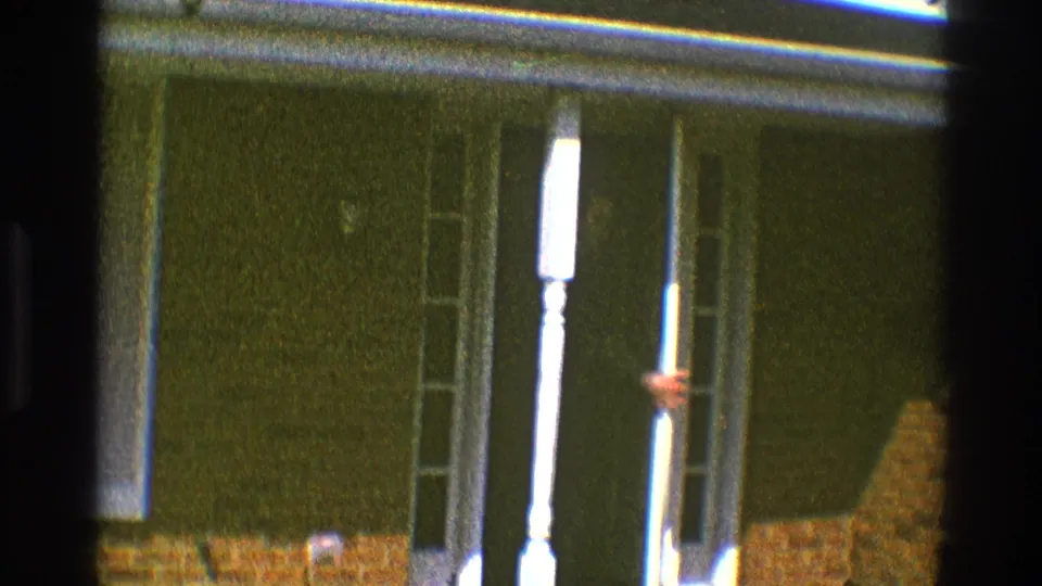 The suited man is mostly hidden behind the white porch column as he disappears into the Clarendon Hills doorway in 1969.