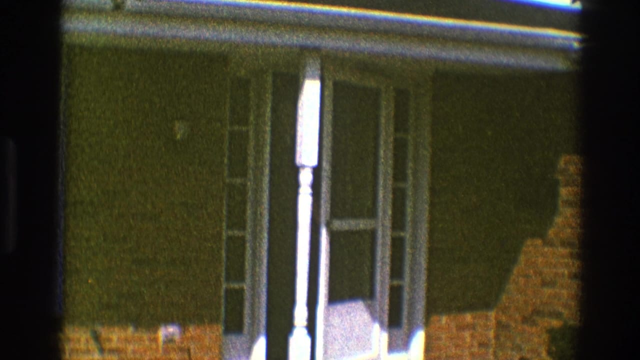 White-framed front door and sidelights beside a dark wall and brick base.