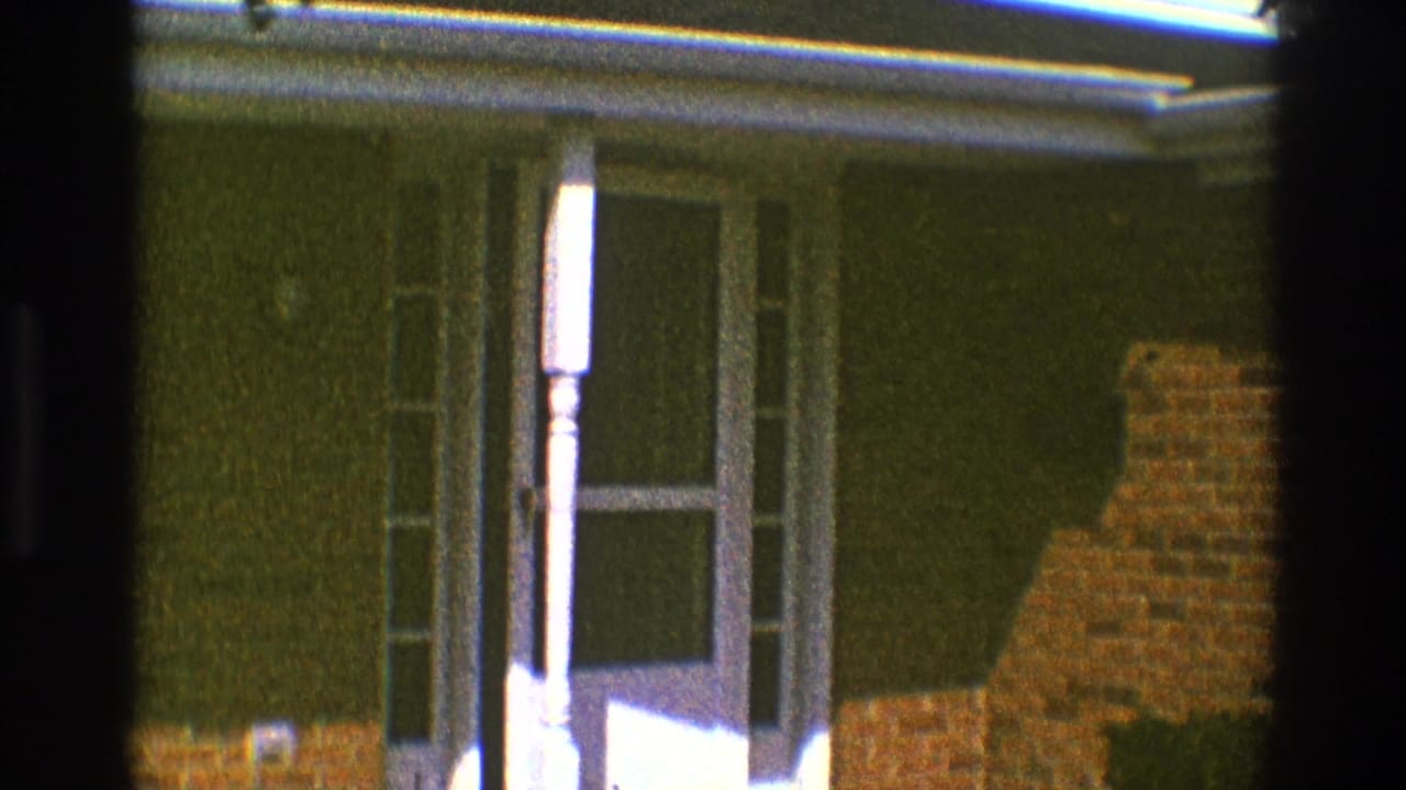 Front door partly open within a white frame, with sidelights and brickwork visible.