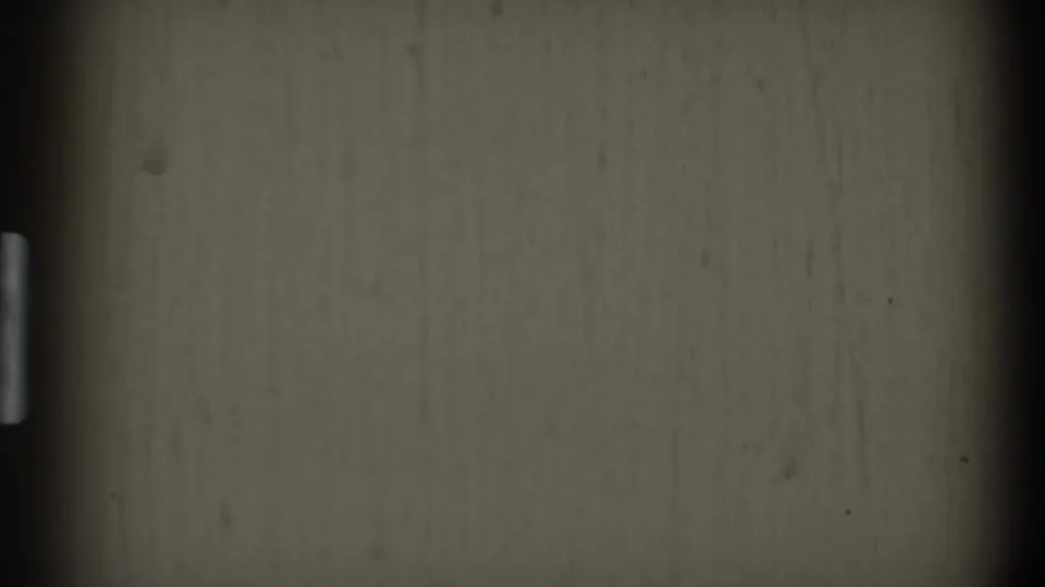 End frame from the 1969 8mm clip showing mostly muted film texture with vertical marks and dark vignette edges after the doorway view drops away.