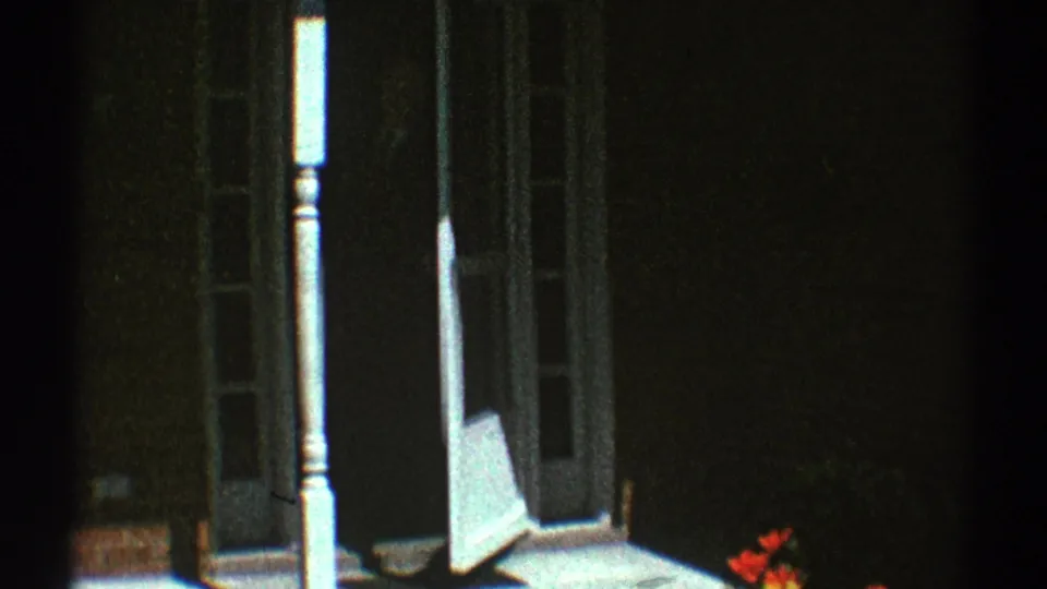 1969 Clarendon Hills porch view with a white screen door, narrow white post, dark entry, and red flowers near the lower right edge.