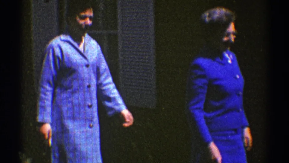 Two women in blue outfits walk outdoors in Clarendon Hills, Illinois, in 1969, one in a light plaid coat and one in a darker suit.