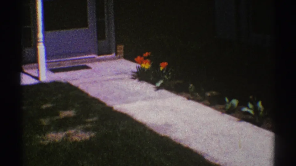 1969 Clarendon Hills frame showing the front entry area, screen door, white post, sidewalk, lawn, and tulip bed.