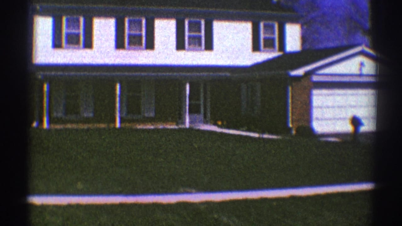 White two-story suburban house with dark shutters, porch, lawn, and garage.