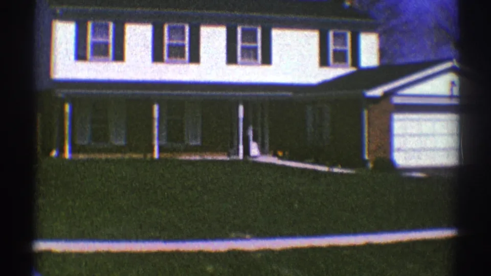 1969 Clarendon Hills home-movie frame showing the house front, shaded porch, lawn, front walk, and garage area.