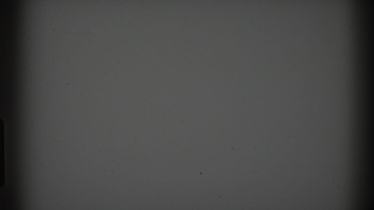 1969 Clarendon Hills 8mm frame showing a blank gray field with gate-edge darkness, dust specks, and a central vertical shadow.