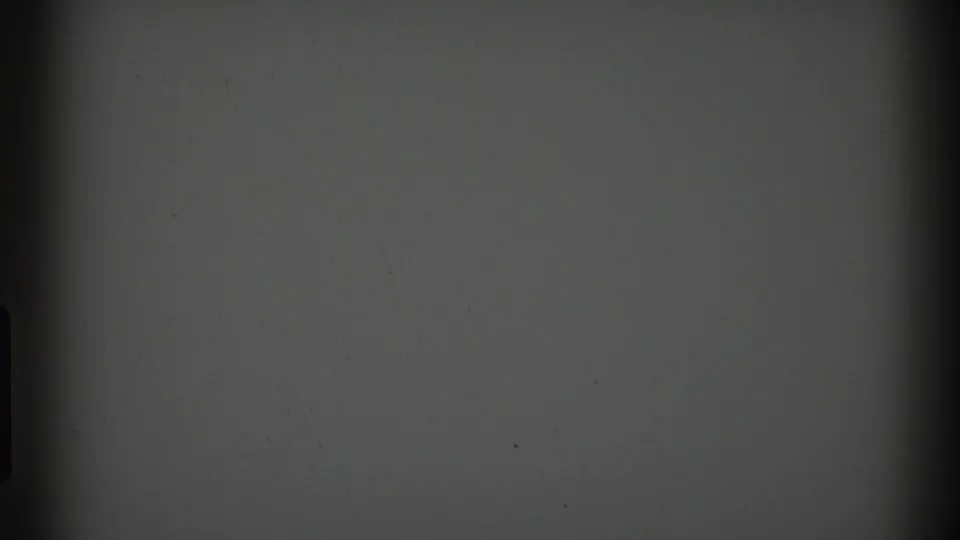 1969 Clarendon Hills 8mm frame showing a blank gray field with gate-edge darkness, dust specks, and a central vertical shadow.