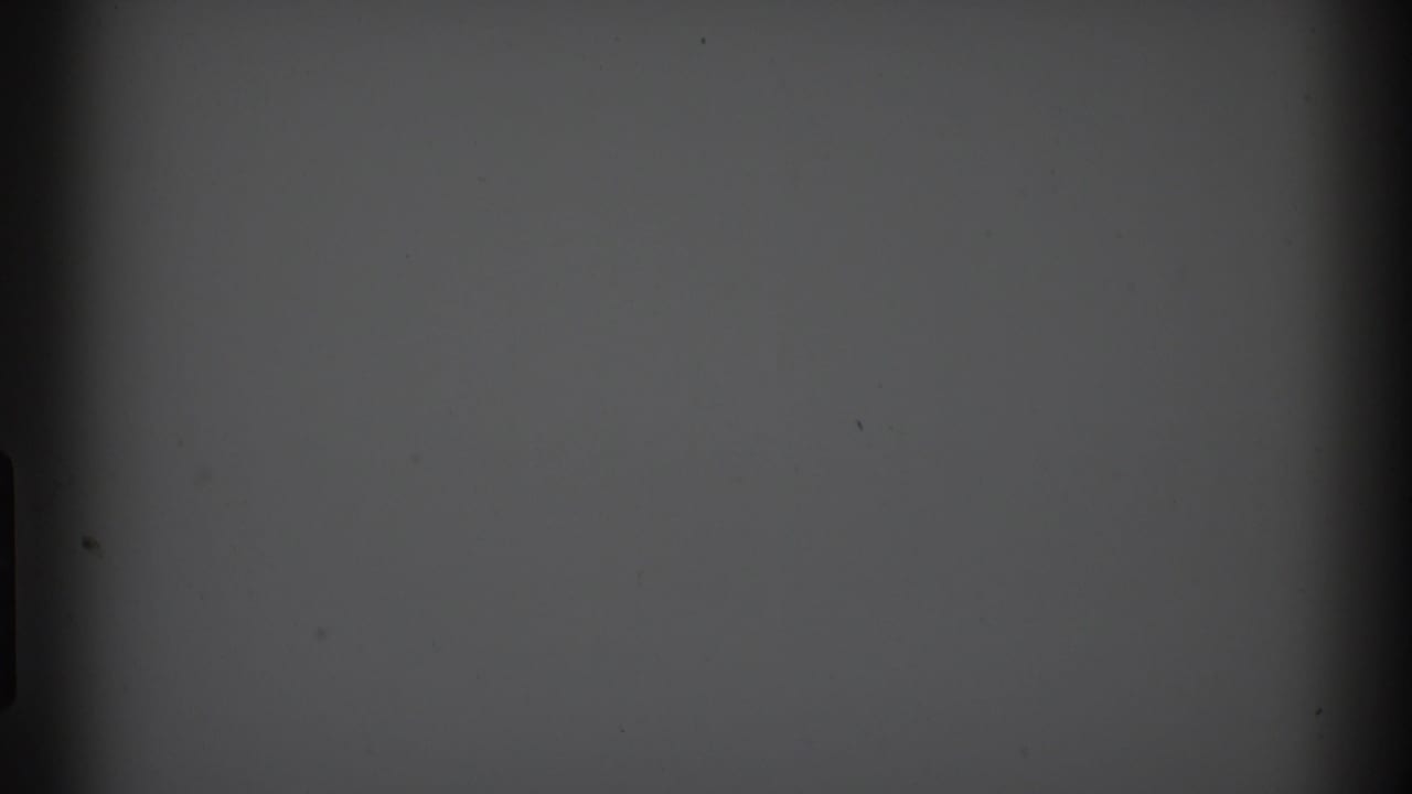 Blank gray film frame with dark side borders, central darkness, and small surface marks.