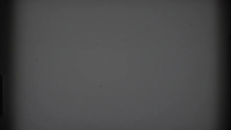 1969 Clarendon Hills 8mm frame showing a flat gray field with black edge marks, dust specks, and subtle exposure variation.