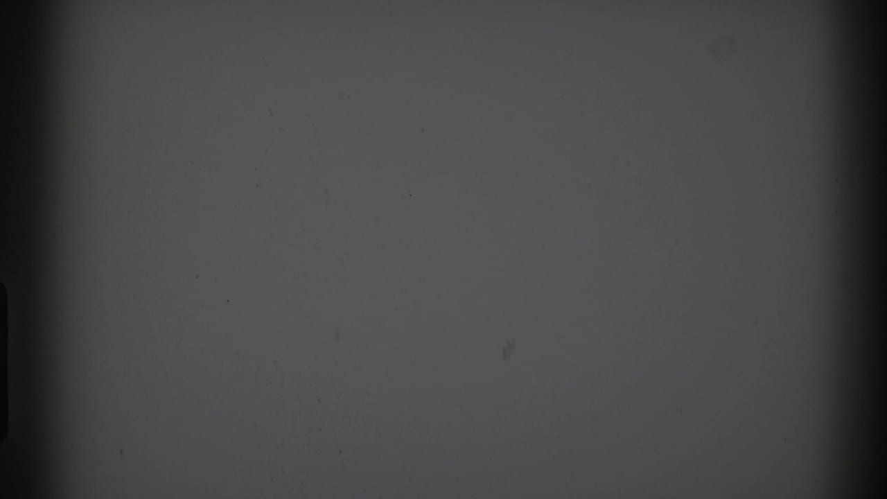 A low-exposure 8mm frame with gray tone, dark edge shapes, and no identifiable people, buildings, or markings visible.