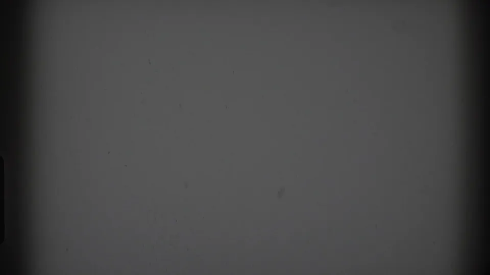 A low-exposure 8mm frame with gray tone, dark edge shapes, and no identifiable people, buildings, or markings visible.
