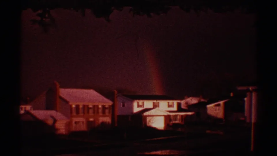 Clarendon Hills residential houses appear under a reddish-purple evening sky, with a faint rainbow rising behind the rooflines.