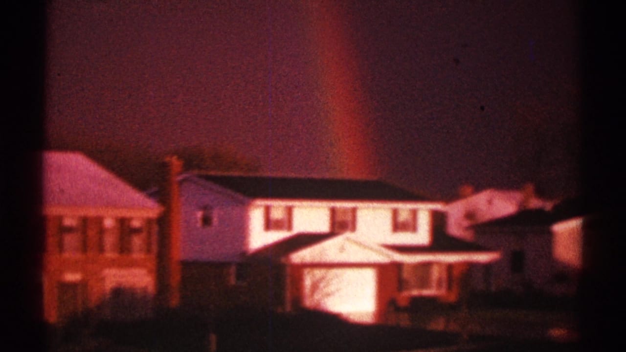 Suburban house row with a faint rainbow rising behind the roofs.